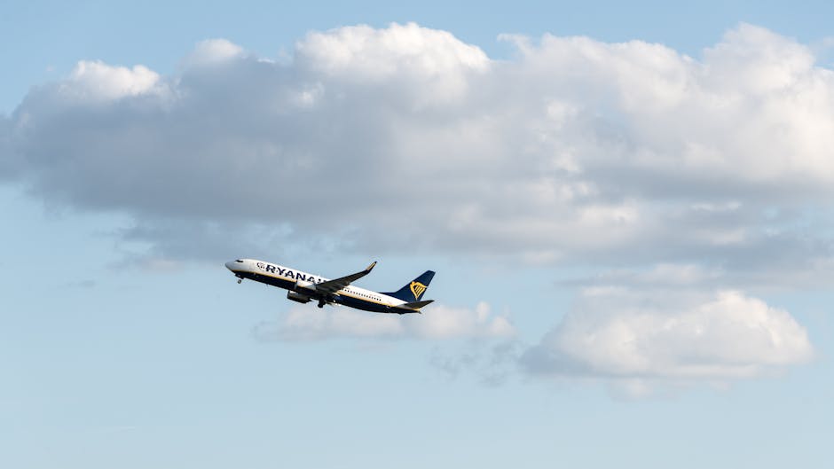 Ryanair airplane taking off into a clear blue sky with fluffy clouds in the backdrop.