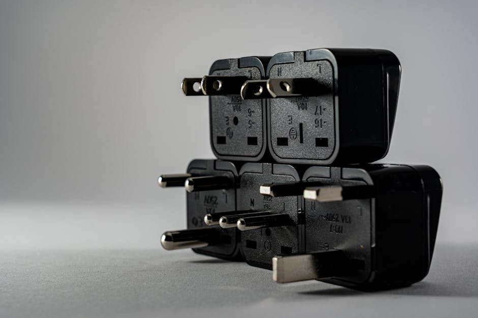 Close-up of black electrical adapters stacked on a gray background.