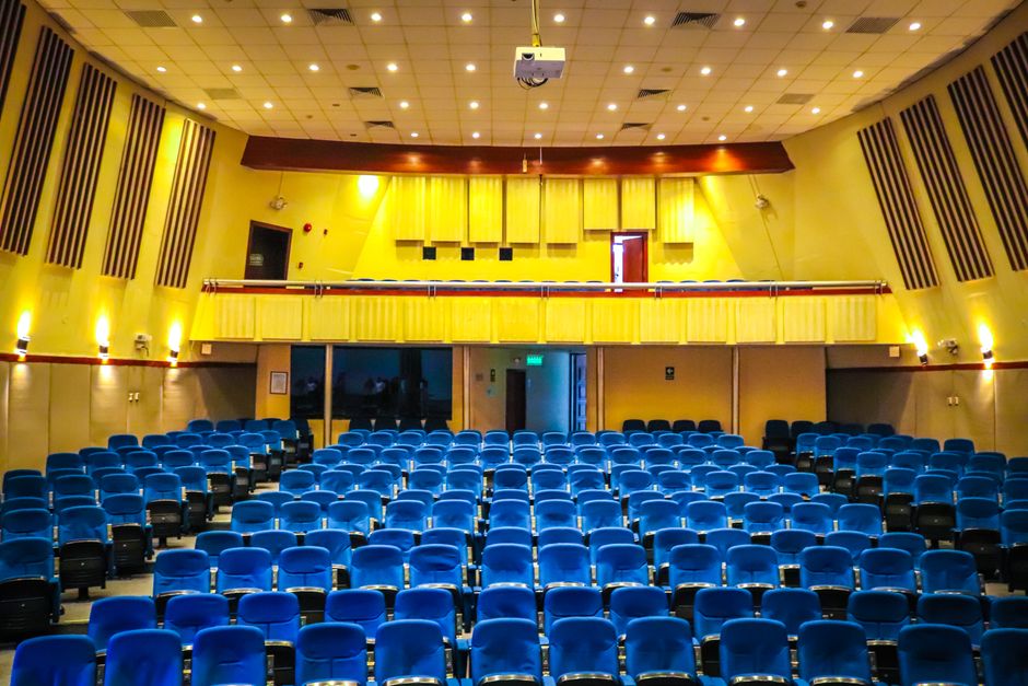 Wide-angle view of a vibrant auditorium with blue seats and yellow walls, perfect for events.