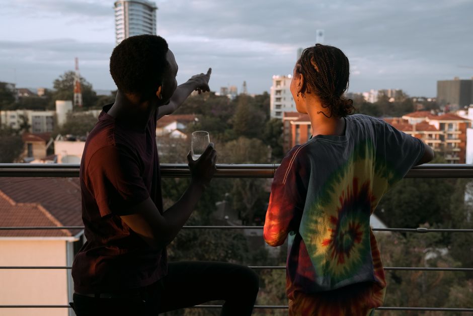 Couple on a balcony relaxing and pointing out city landmarks at sunset.