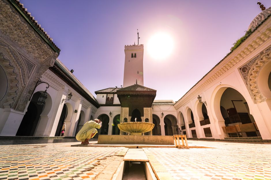 A stunning historical courtyard with a central fountain, showcasing Islamic architecture in bright daylight.
