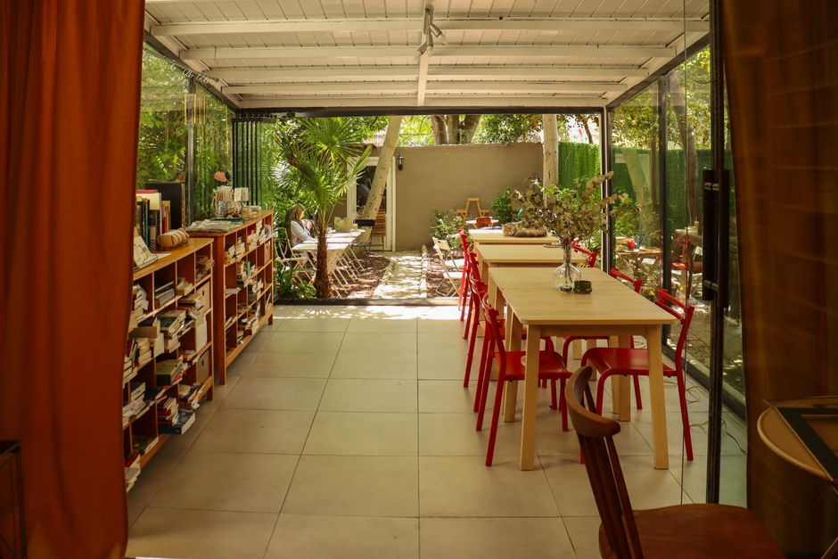 Inviting indoor-outdoor space with bookshelves, tables, and garden view, perfect for relaxation.