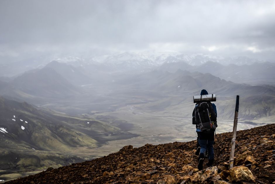 A lone hiker treks through Landmannalaugar, Iceland, showcasing breathtaking mountain landscapes.