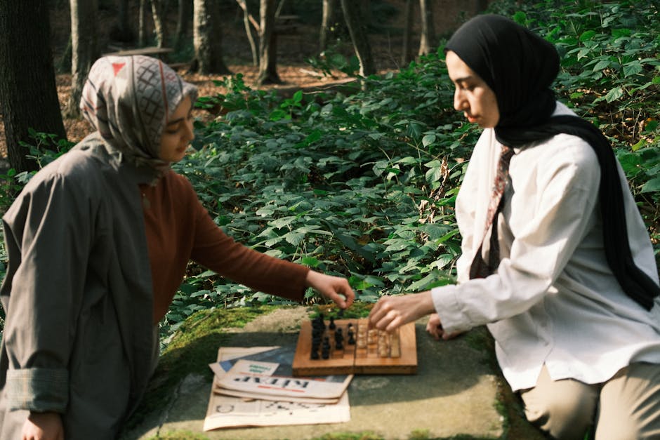 Two women engaged in a chess game outdoors in a serene forest.