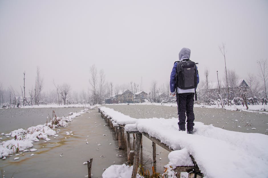 A child walks on a snow-covered bridge in the serene winter of Kashmir.