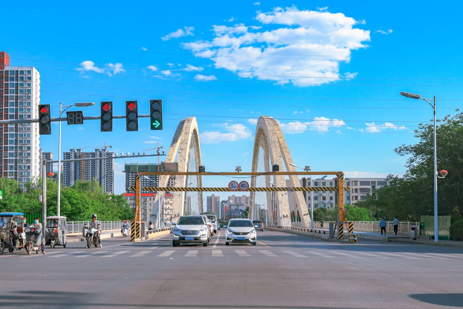 Street view of a busy urban bridge in Pingdingshan, Henan, China with vehicles and pedestrians under a clear blue sky.