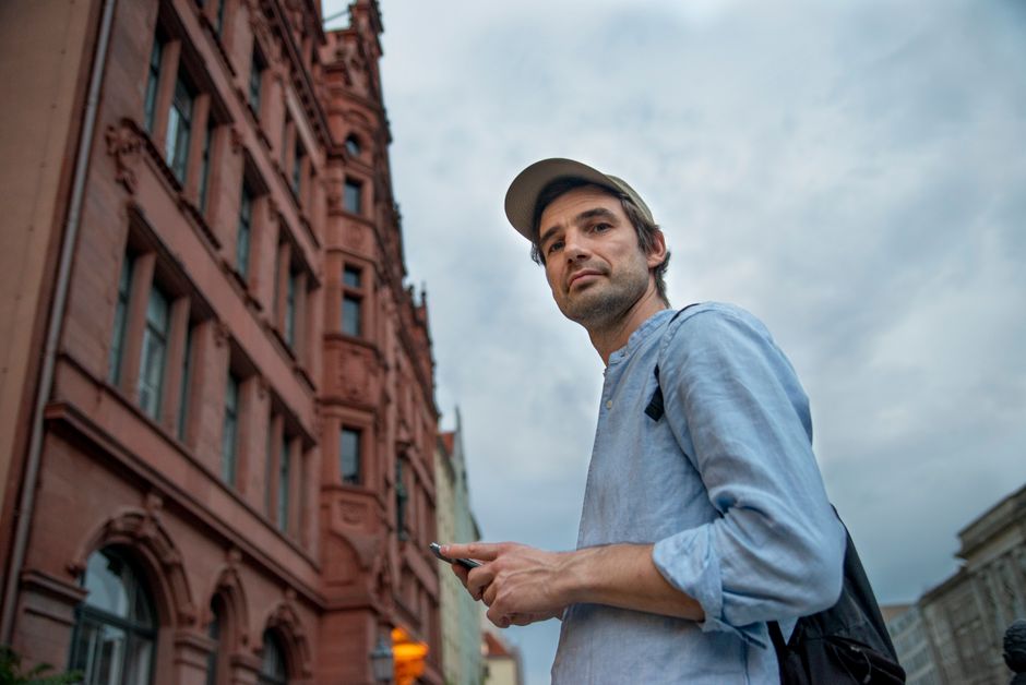 Casually dressed man using smartphone in Berlin city street with historic architecture